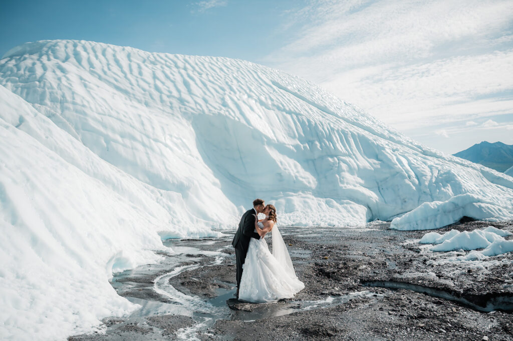 bride and groom kissing surrounded by the matanuska glacier