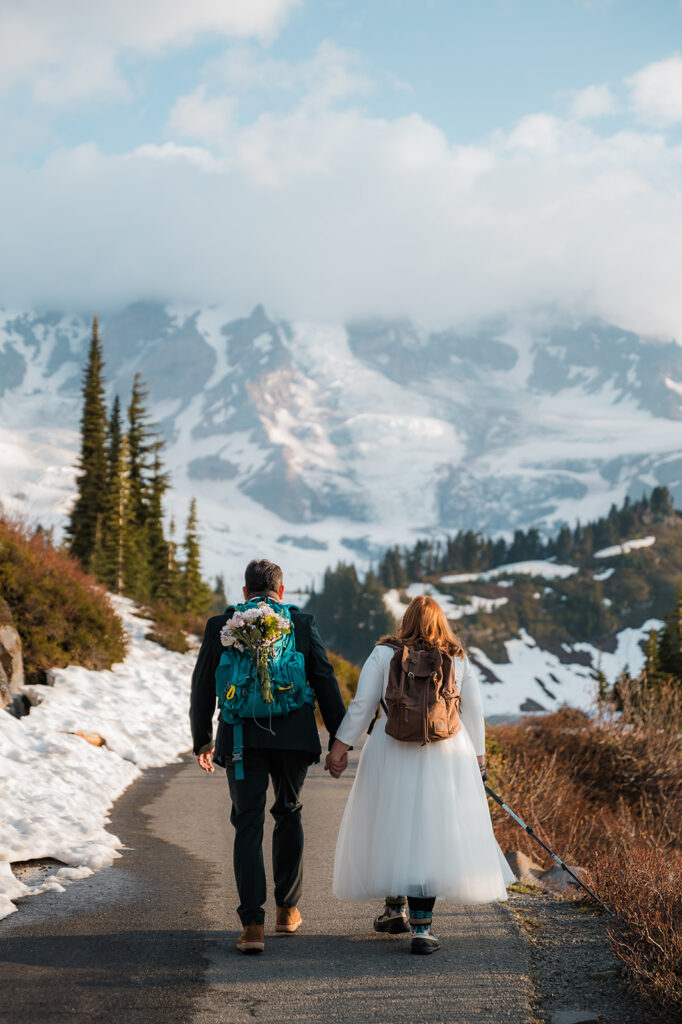 couple wearing backpacks and hiking on their elopement day at Mt. Rainier National Park