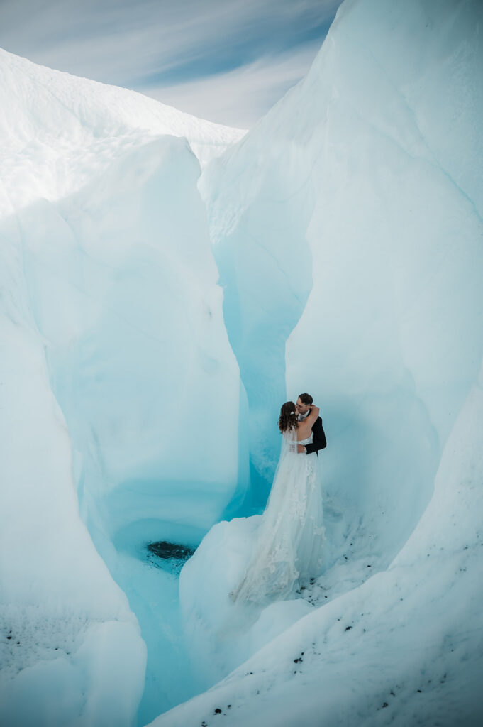 bride and groom surrounded by glacial ice and a waterfall on the matanuska glacier on their elopement day 