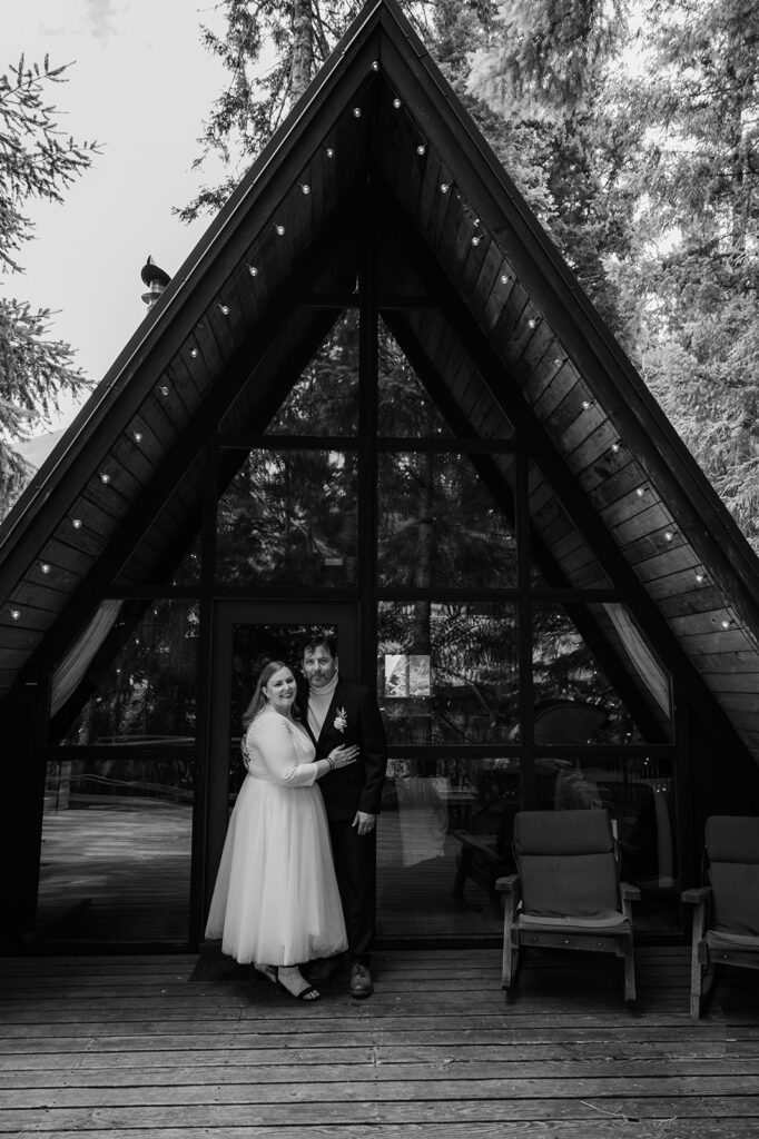 newly married couple standing in front of their a frame cabin in Packwood Washington after spending their elopement day hiking at Mount Rainier National Park