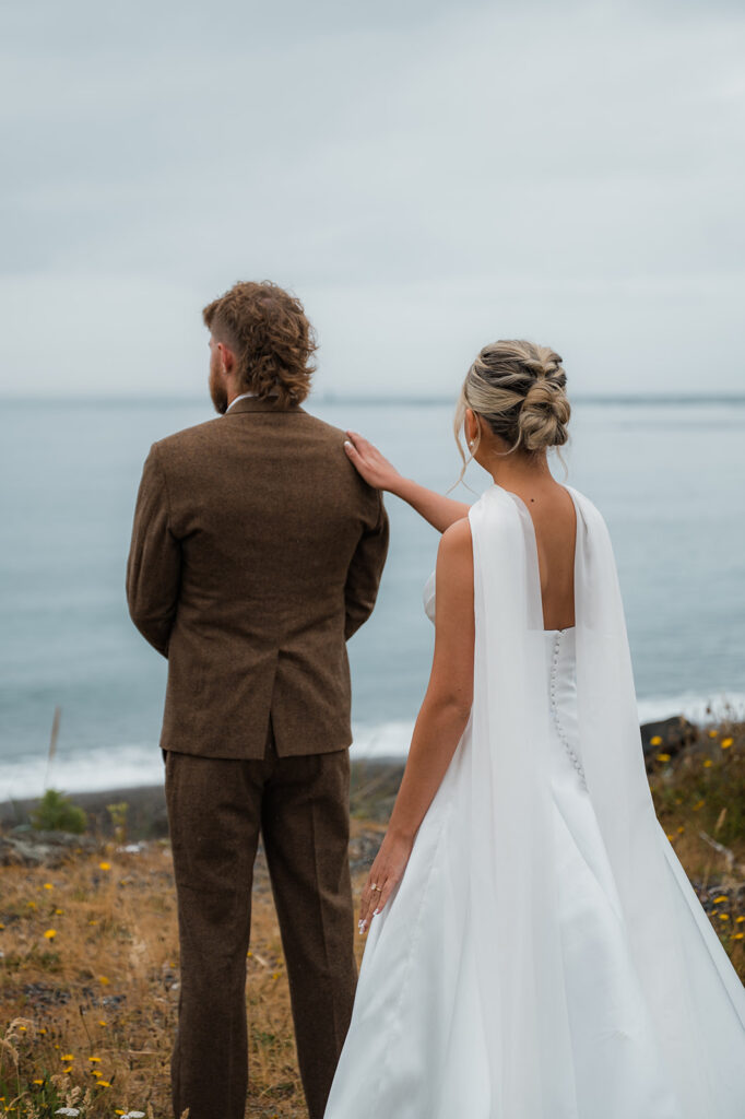 bride tapping the groom on the shoulder for their first look on their moody PNW elopement day