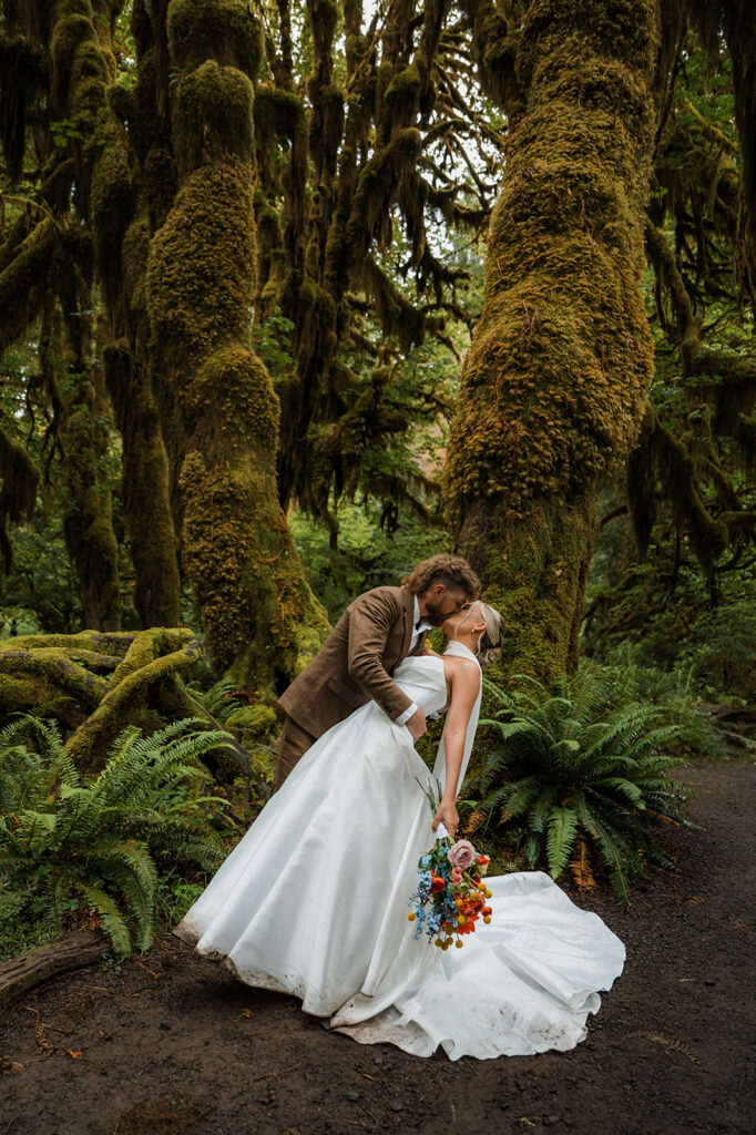 bride and groom kissing surrounded by mossy trees and ferns in the Hoh Rainforest