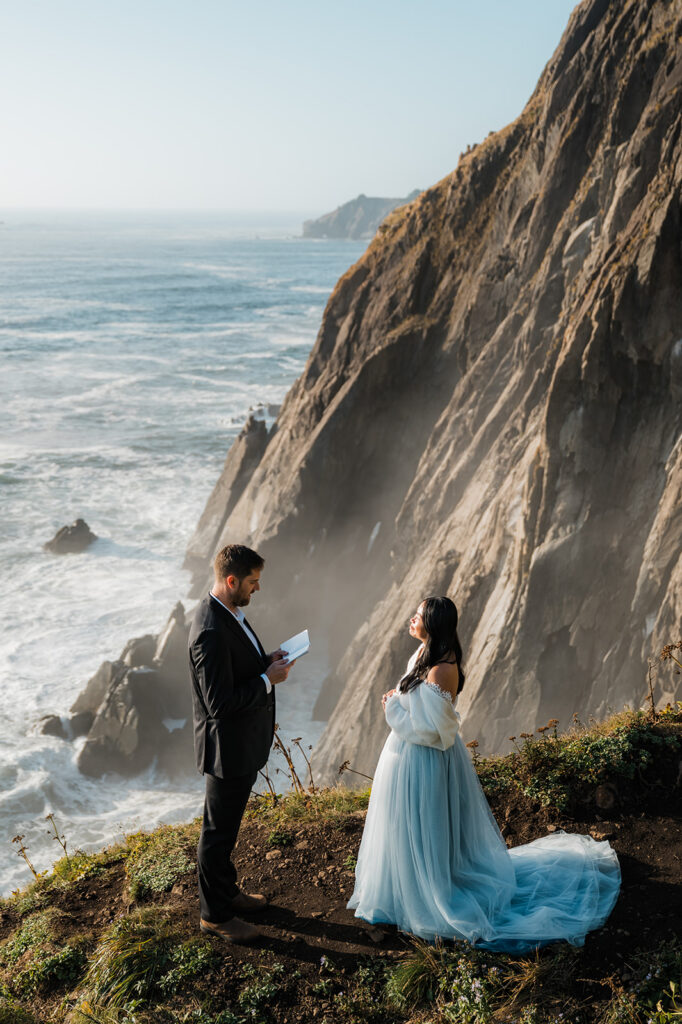 groom reading his vows with views of the cliffs in the background during an Oregon coast vow renewal at Elk Flats