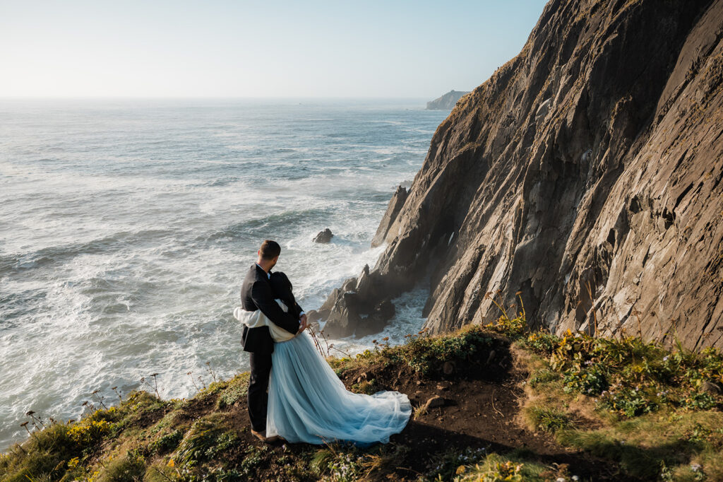 couple hugging and enjoying the view of the cliffs during their oregon coast vow renewal at elk flats 