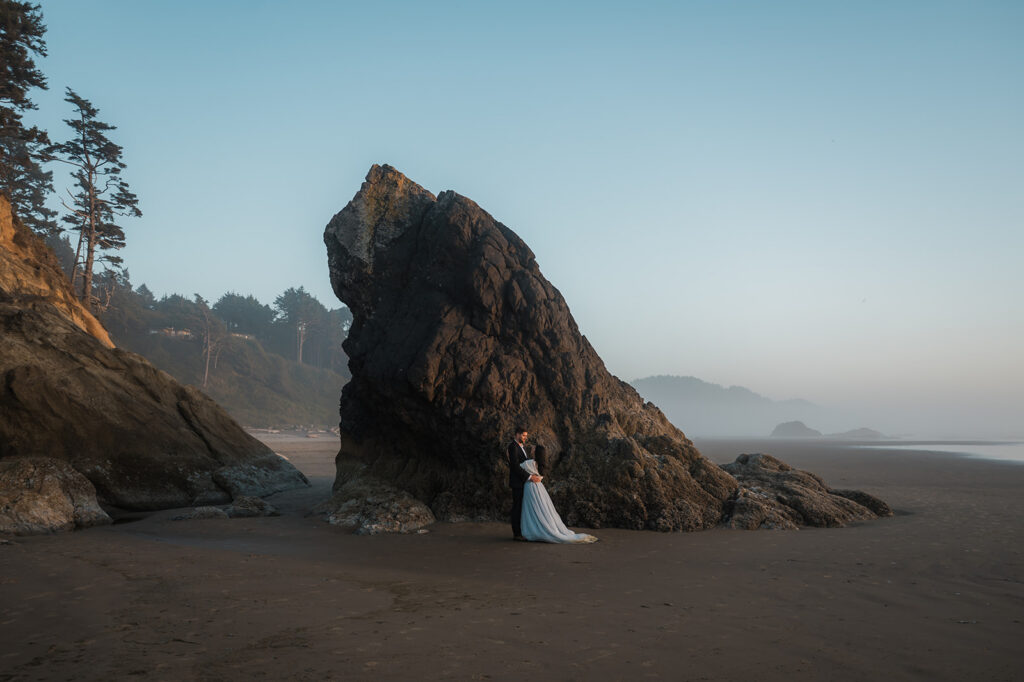 couple kissing with a sea stack in the background during their Oregon coast vow renewal at hug point