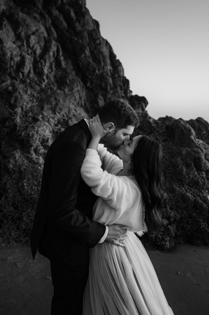 black and white photo of a couple kissing with a sea stack in the background during their Oregon coast vow renewal