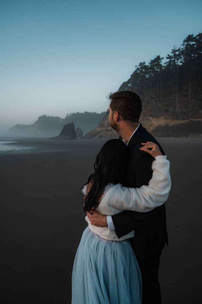 couple standing together and watching the sunset on their Oregon coast vow renewal day at hug point