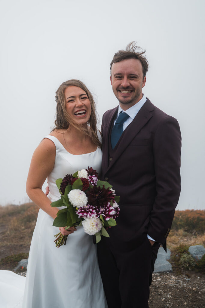 Bride holding bouquet in misty mountain landscape at Mt. Rainier