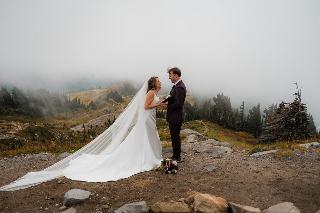 Couple reading vows with misty mountain views during Mt. Rainier elopement