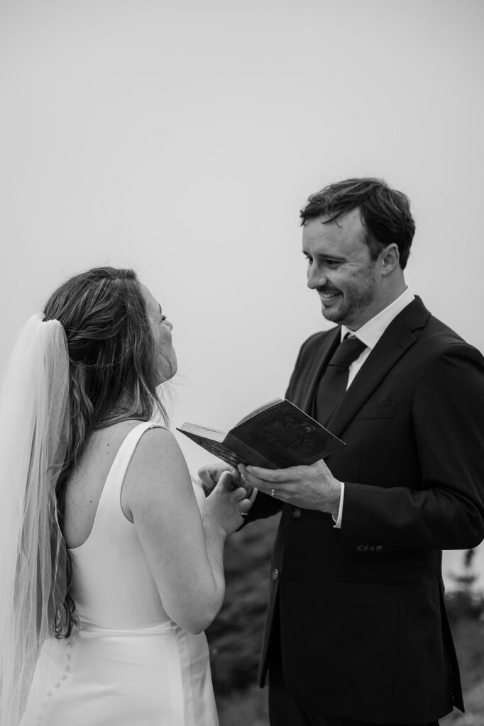 Mt. Rainier elopement couple reading vows with foggy mountain backdrop