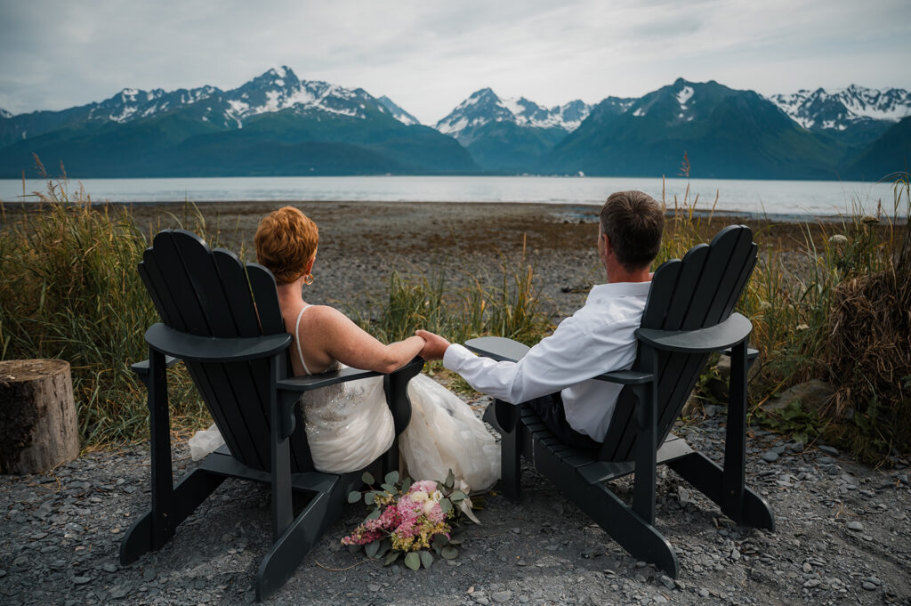 Couple holding hands and looking out at the rocky beach during their Seward Alaska elopement